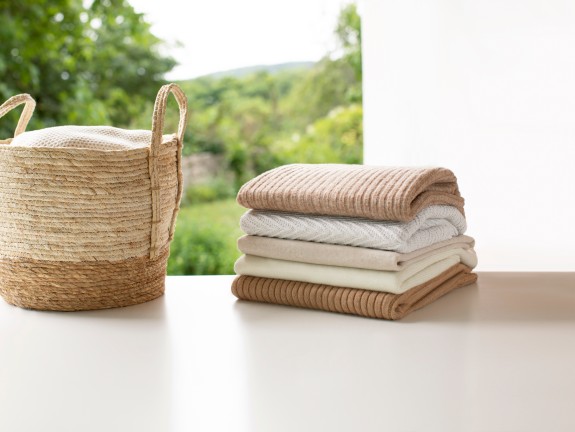 Gestapelte Handtücher liegen neben einem Korb mit Wäsche